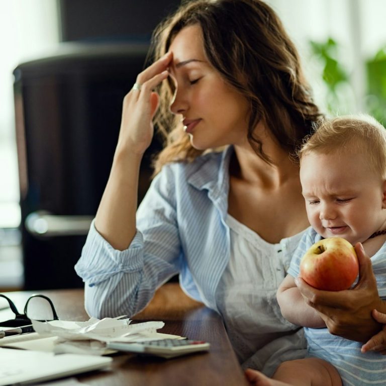 Woman sitting at a desk, looking concerned and uncomfortable while working on a laptop..