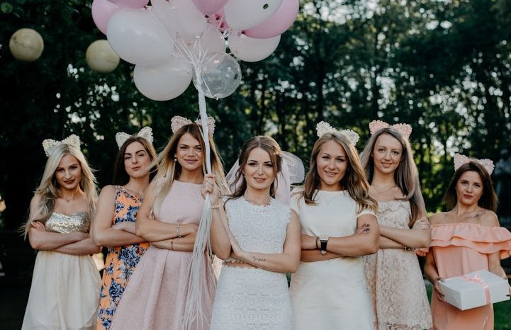 Group of women at a hen party with balloons, posing confidently in a garden setting.