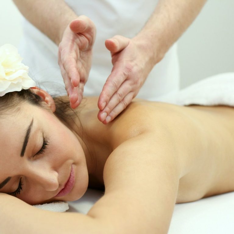 A woman receiving a massage, relaxing with a flower in her hair.